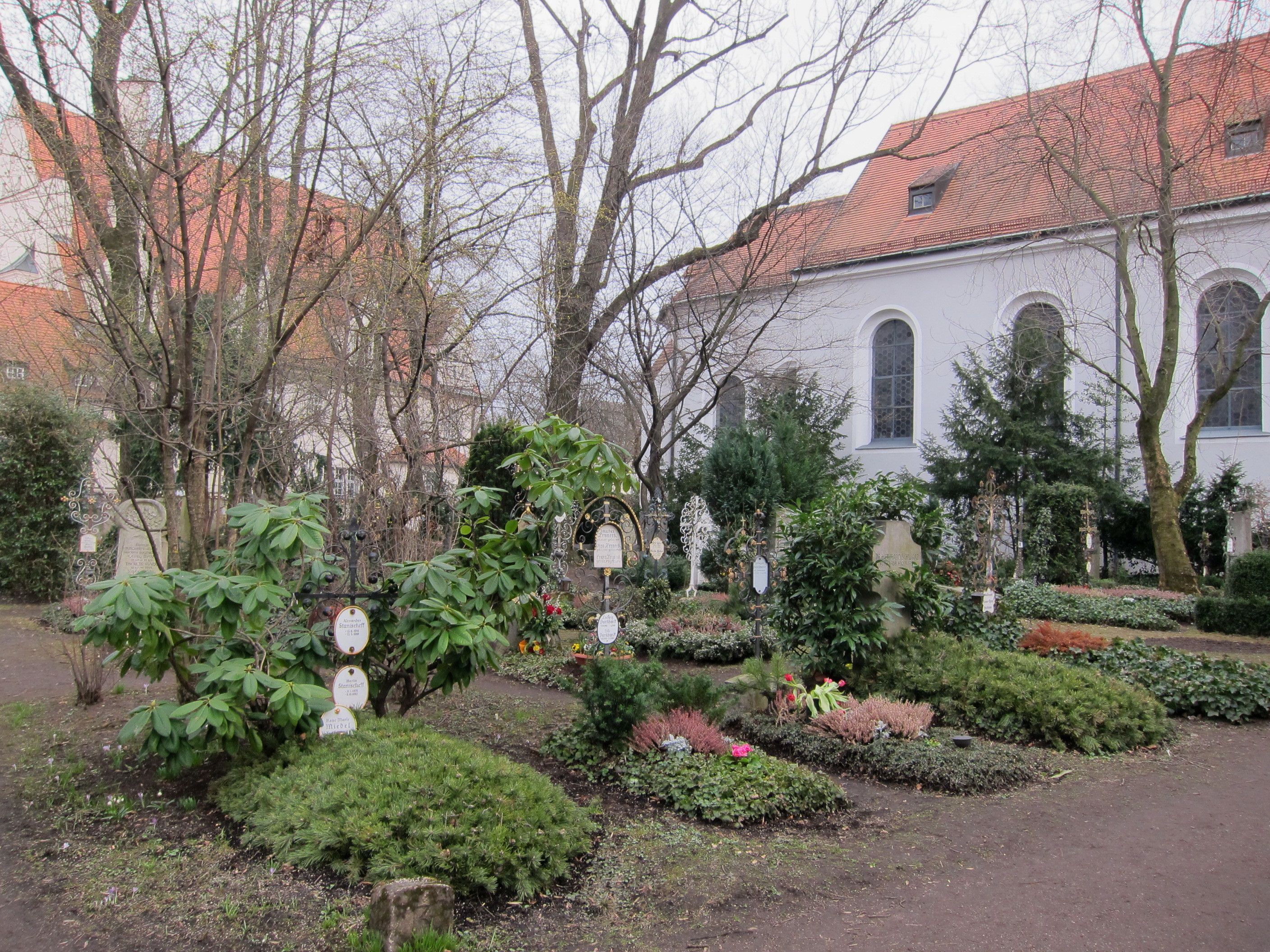 Historische Grabzeichen und gepflegte Bepflanzung am ummauerten Friedhof Bogenhausen